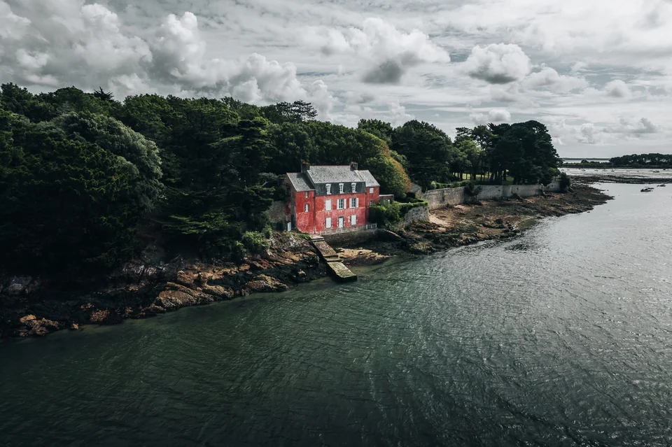 Maison rose au bord de l’eau et des arbres sur la côte de Bretagne