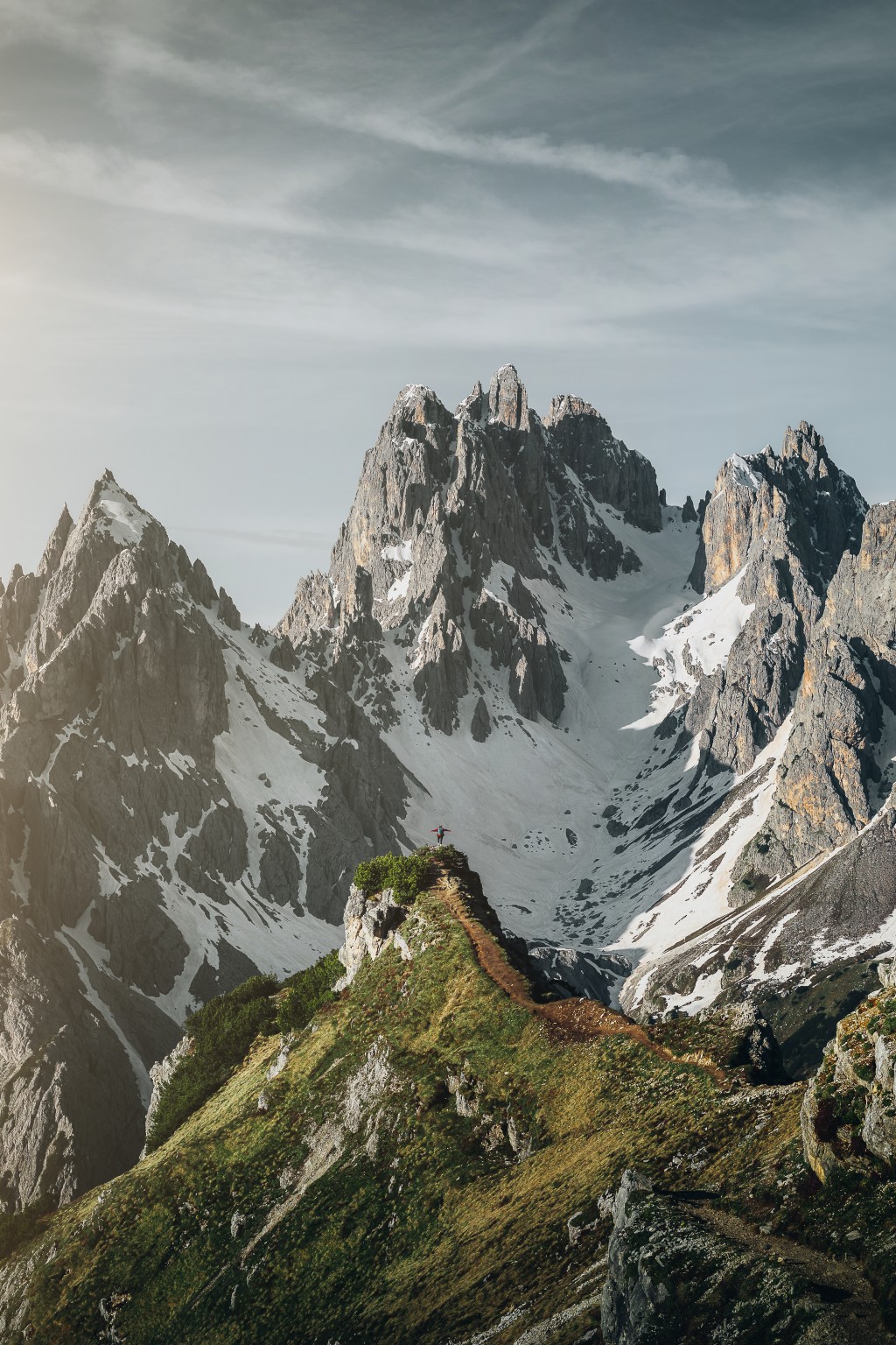 Silhouette sur une crête herbeuse devant les sommets enneigés des Dolomites