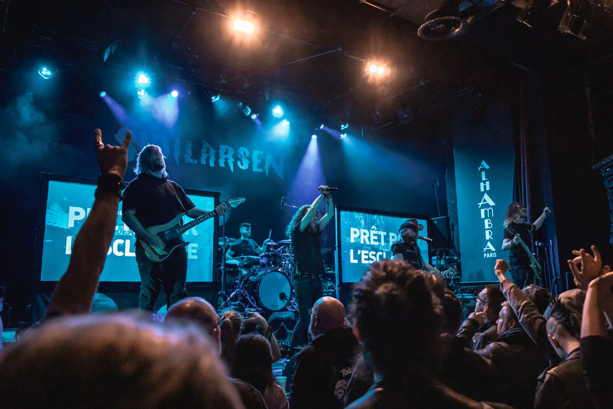 Groupe de rock sur scène devant le public, éclairé de bleu