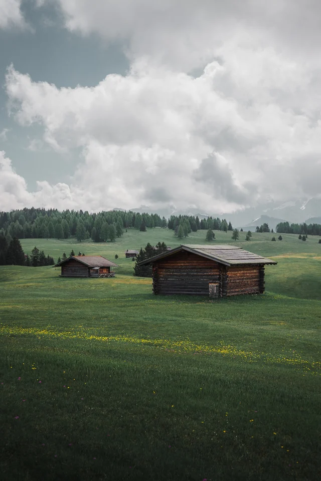 Chalets dans un alpage des Dolomites sous de grands nuages