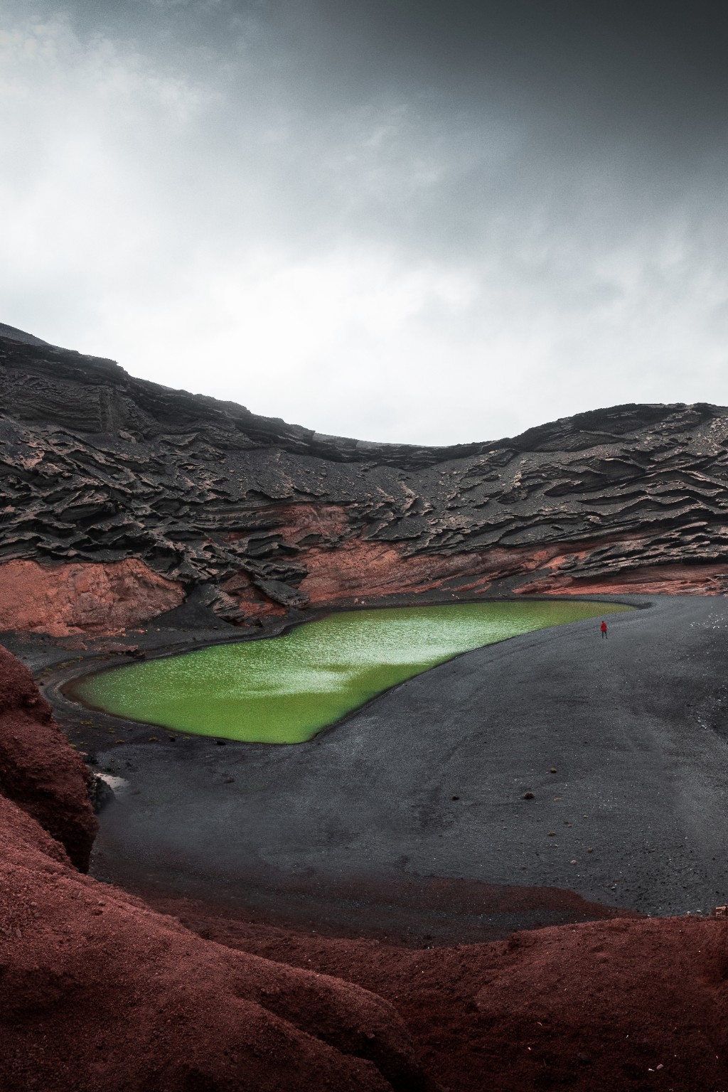 Lagune verte entre les roches rouges et le sable noir à Lanzarote