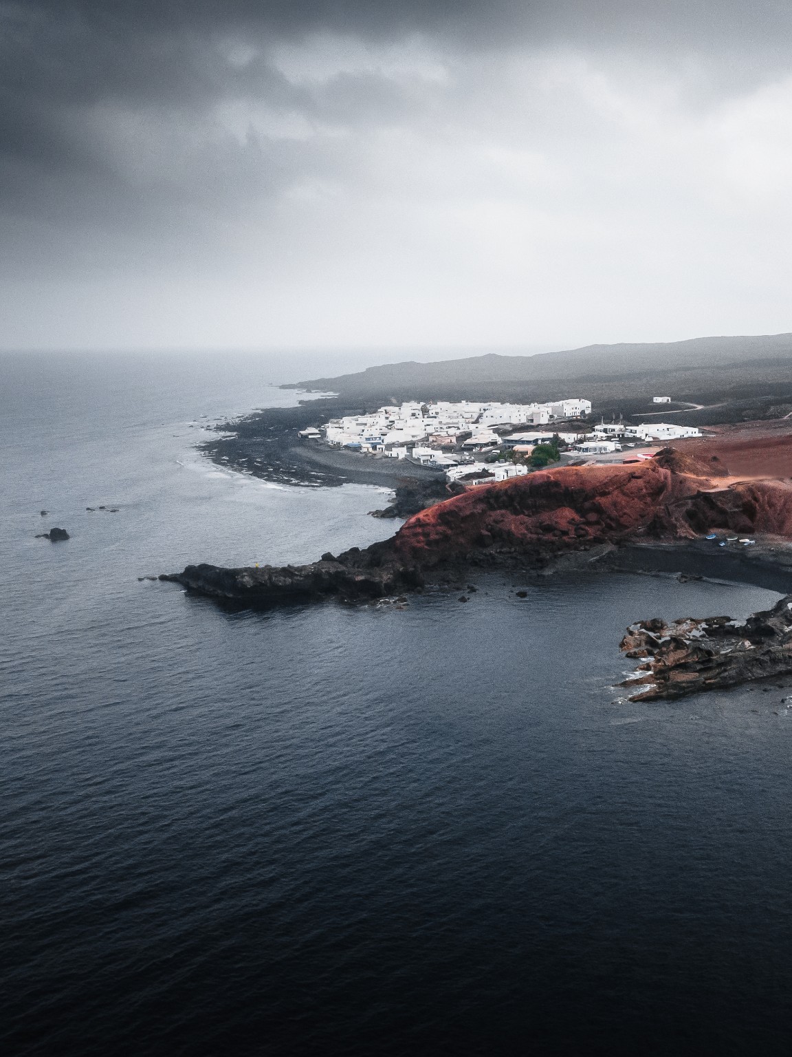 Village blanc sur le littoral volcanique de Lanzarote, entre mer et roches rouges
