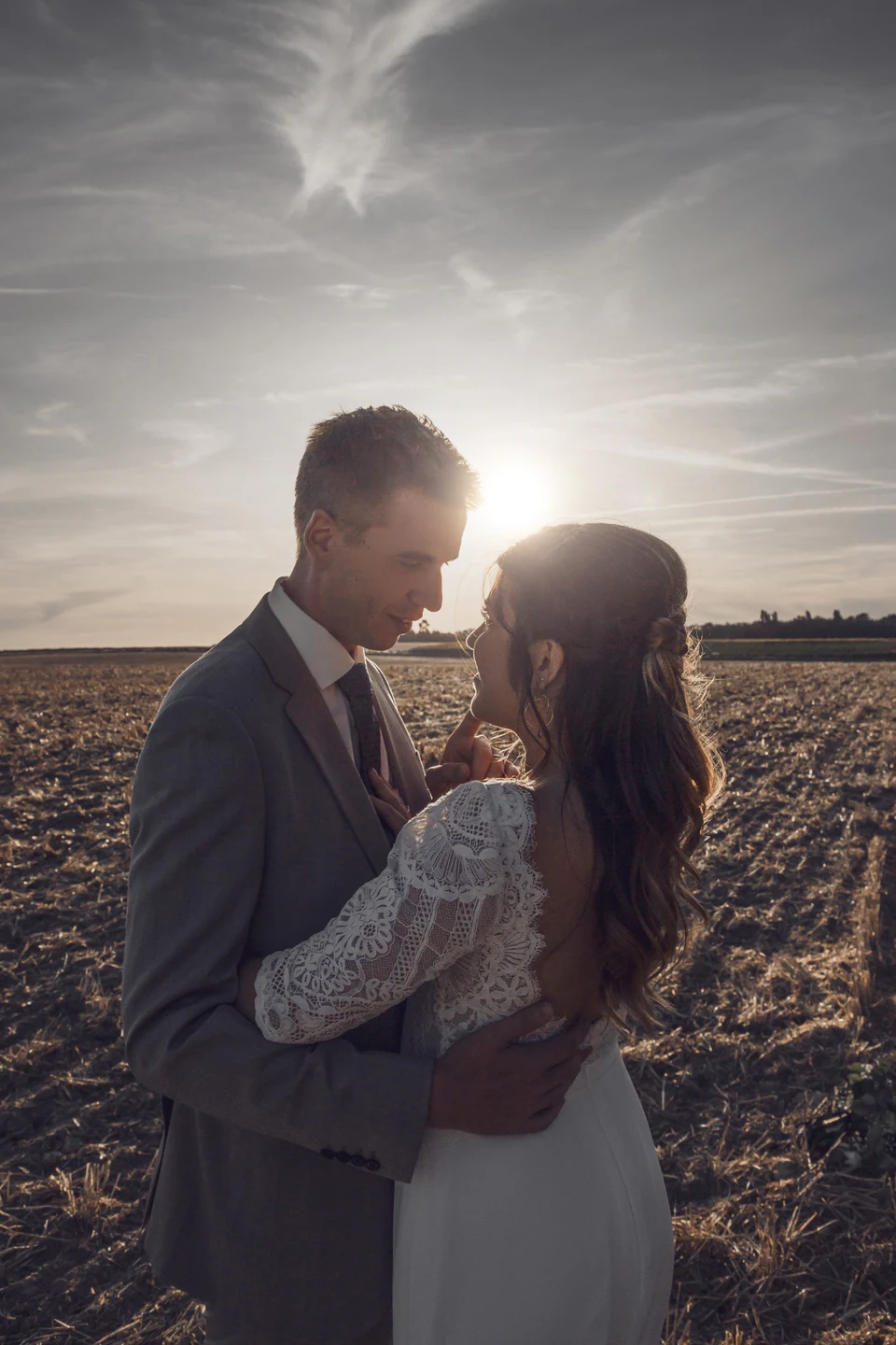 Portrait des mariés dans un champ, face au soleil