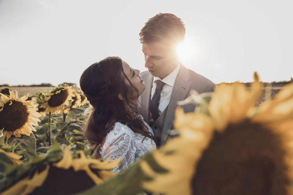 Les mariés se regardent dans un champ de tournesols au soleil couchant