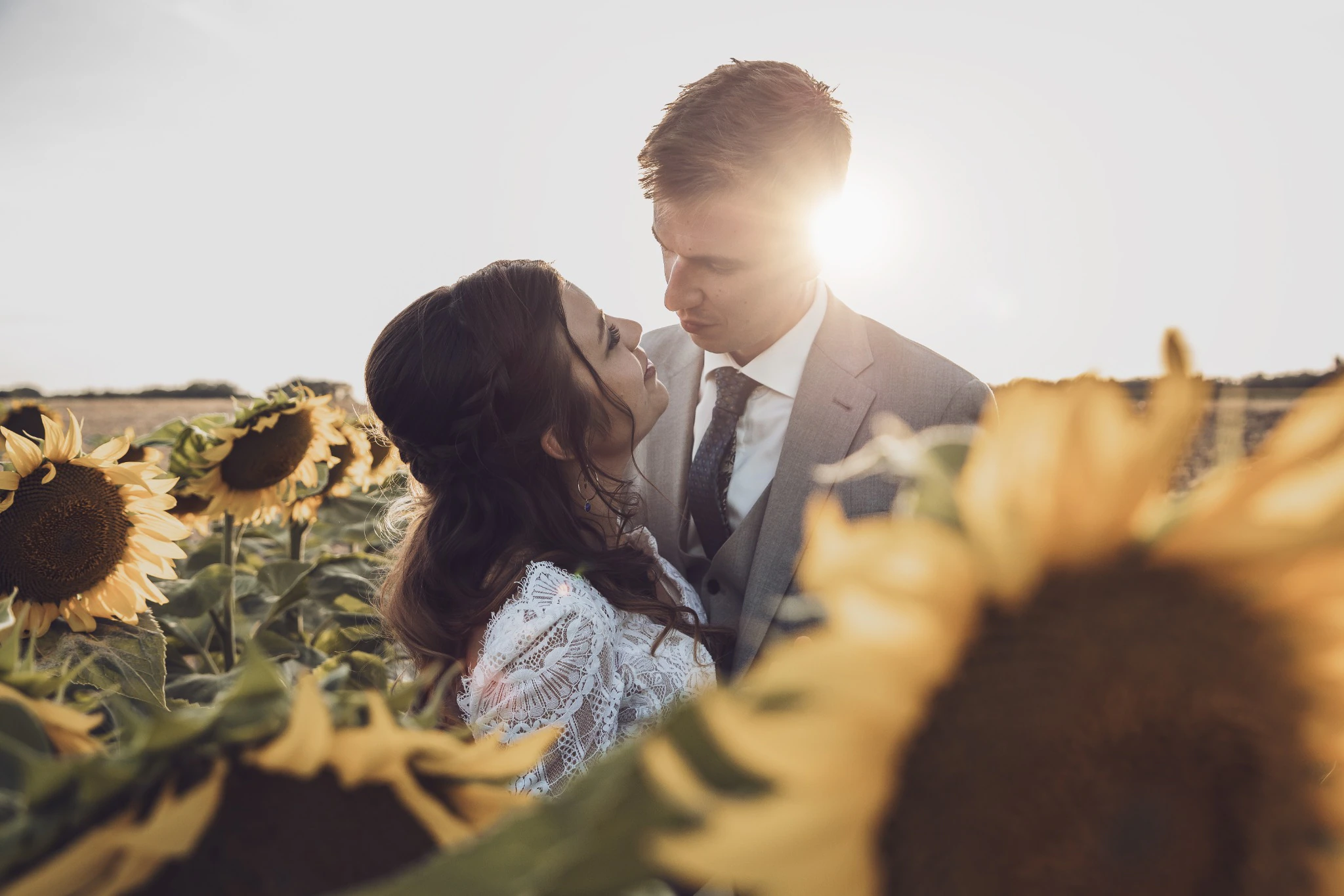 Les mariés se regardent dans un champ de tournesols au soleil couchant