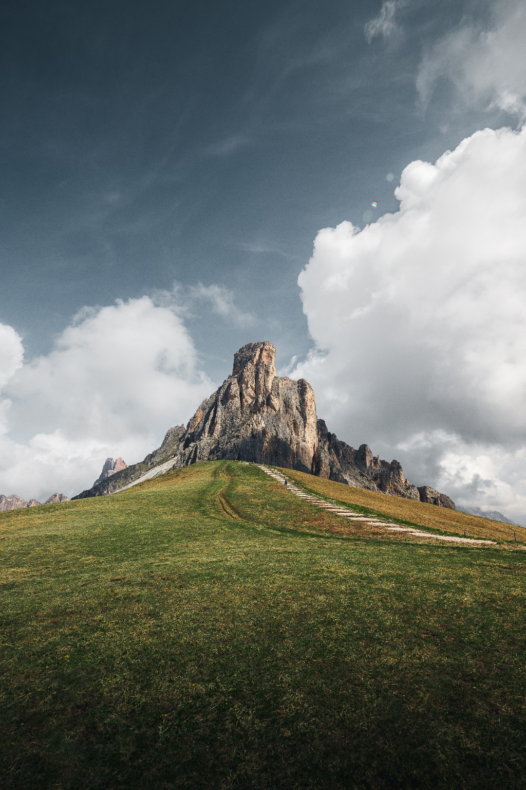 Sommet rocheux dominant un alpage verdoyant sous les nuages