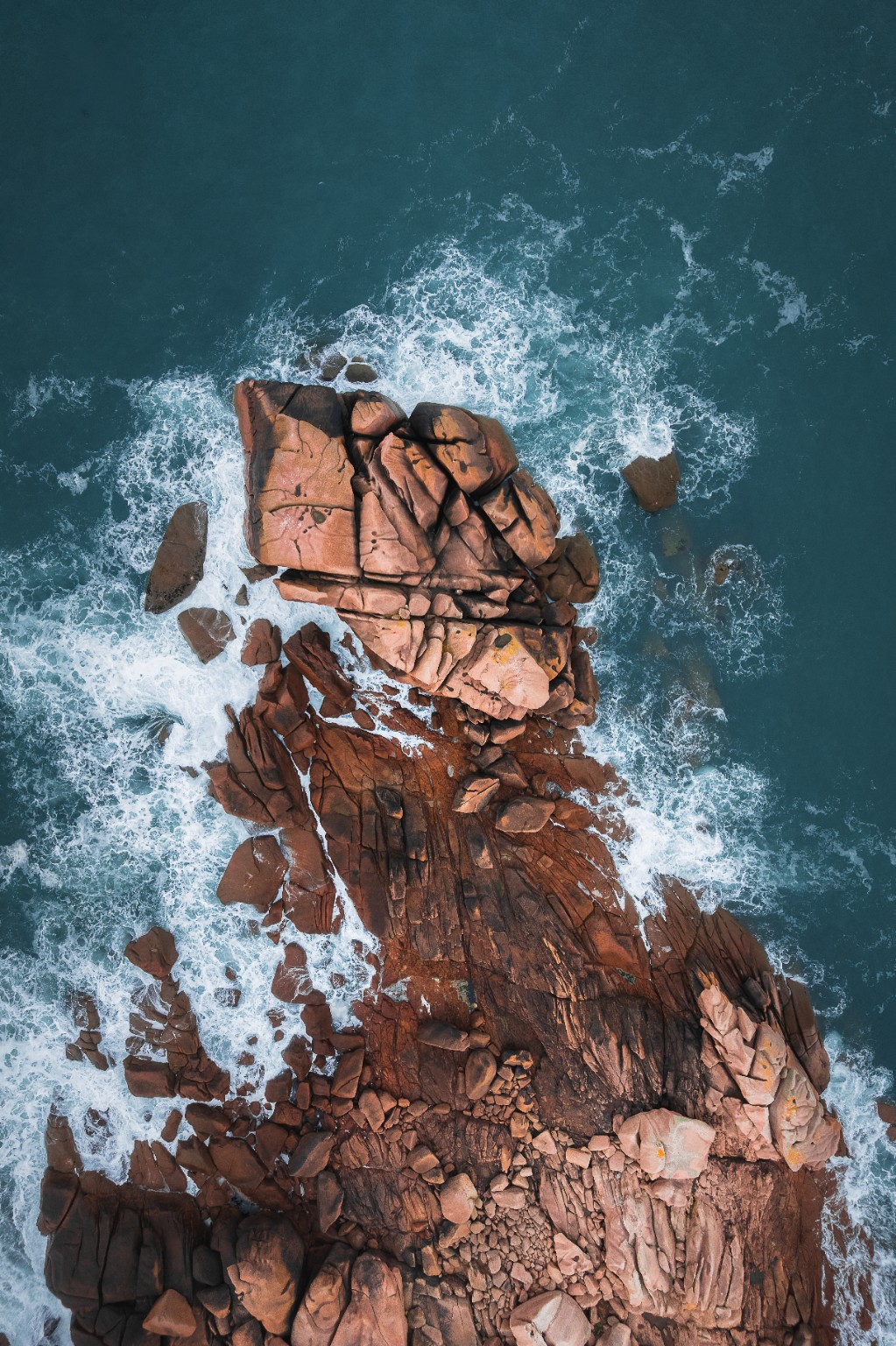 Rochers de granit rose entourés par les vagues, vus du ciel