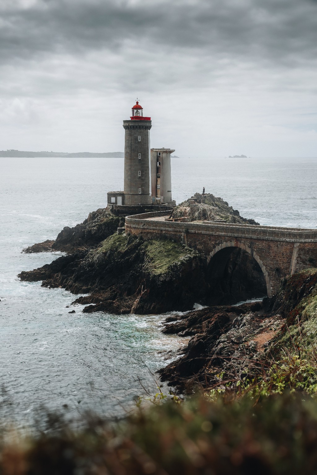 Phare à lanterne rouge et pont de pierre au-dessus de la mer