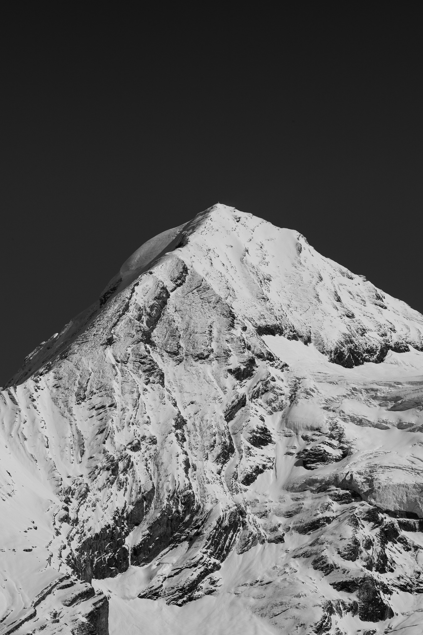 Sommet enneigé en noir et blanc sous un ciel sombre