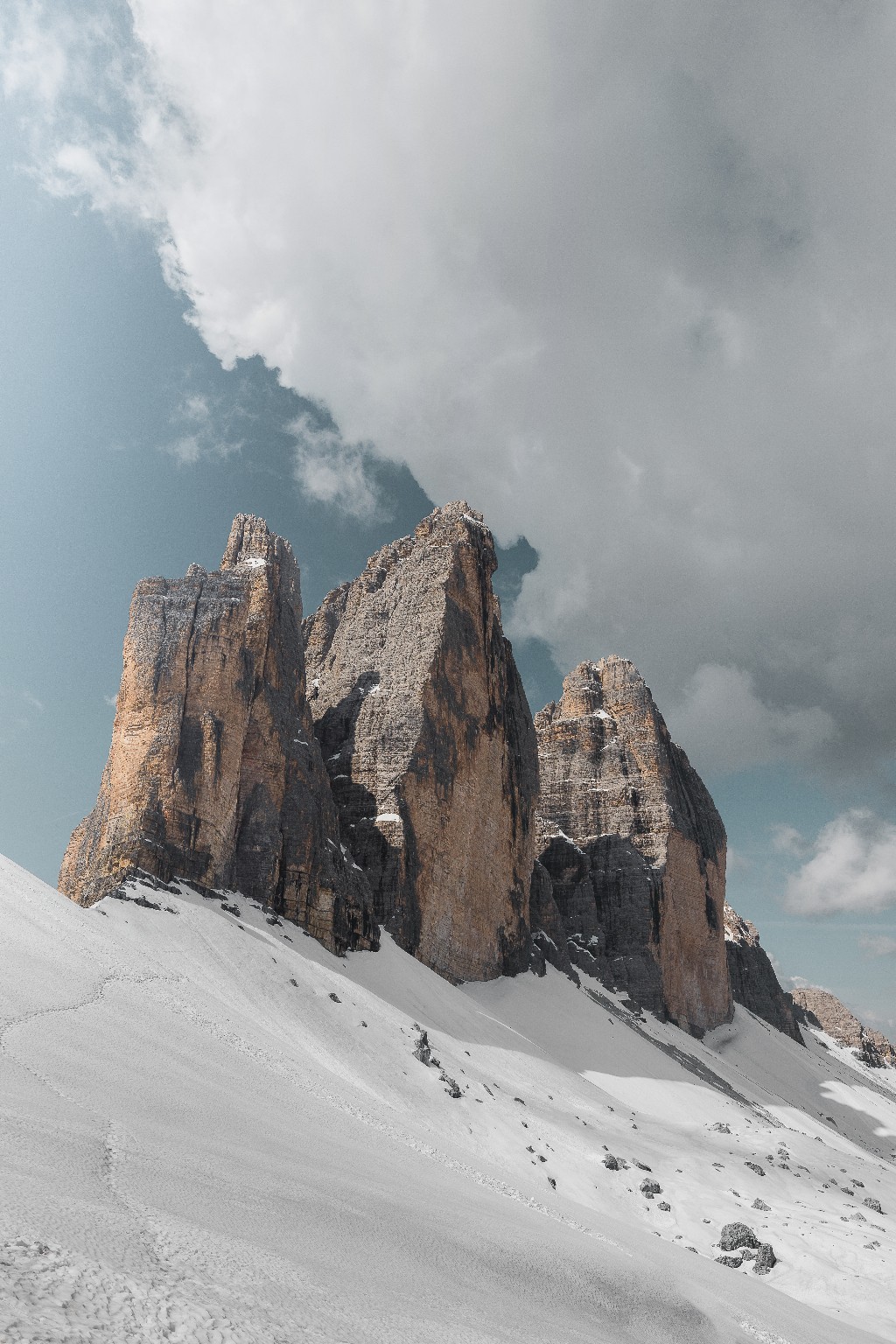 Trois tours rocheuses des Dolomites au-dessus de pentes enneigées